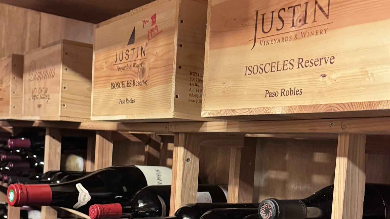 Original wooden wine cases stored intact on warehouse racking above bottle shelving