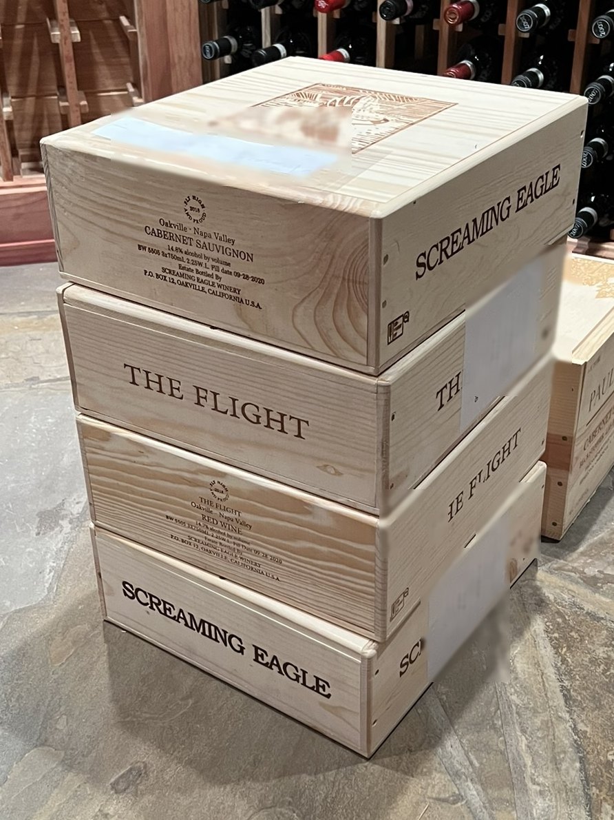 Original wooden cases of wine stacked on a stone floor inside a private cellar after delivery